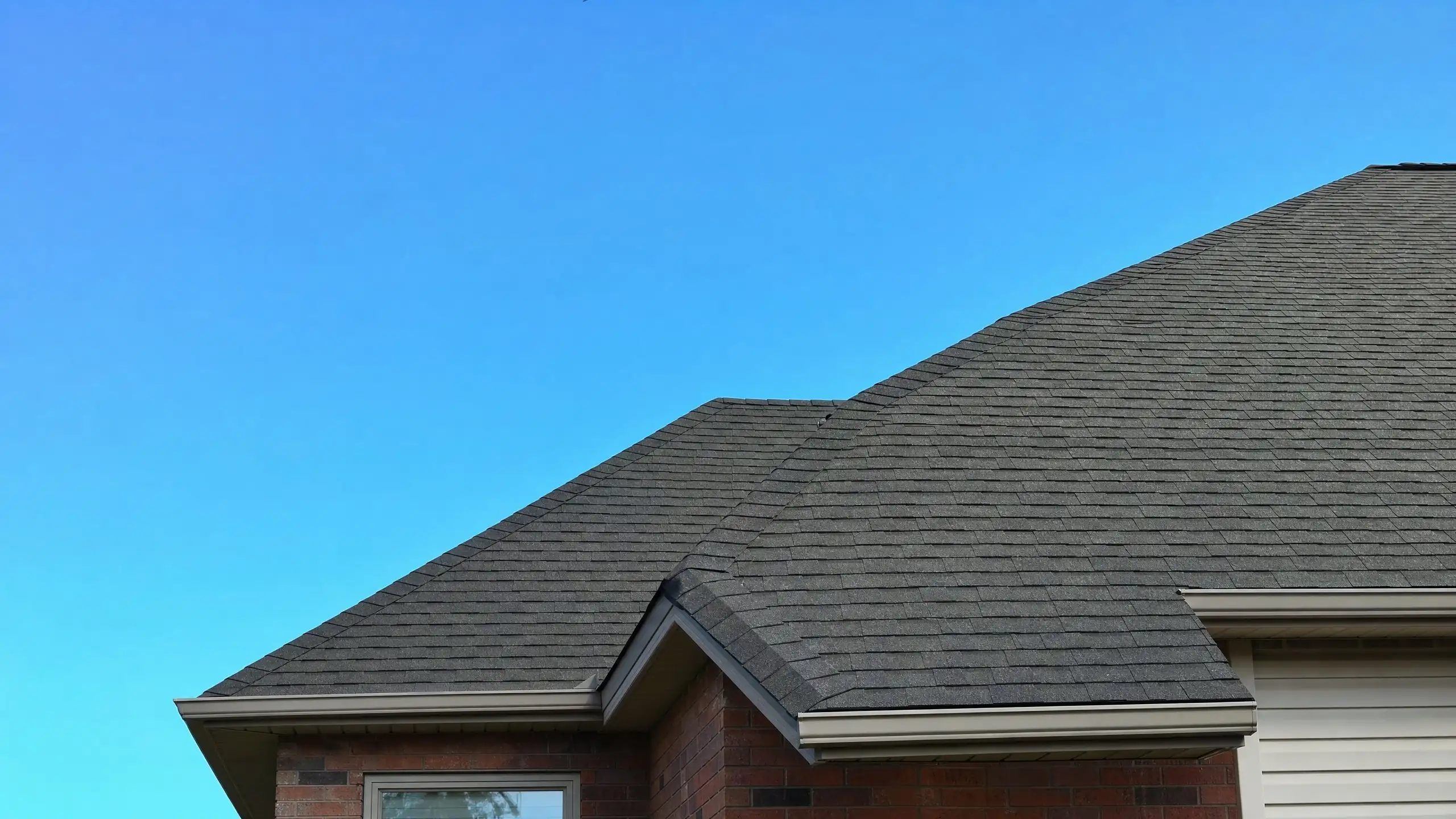 Close view of a new addition roof woven into an existing roof at a clean valley with matching shingles