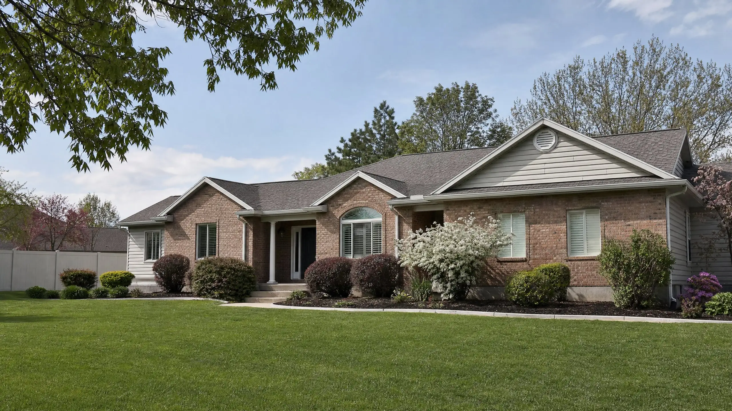 Well-kept home with a matching side addition, blooming shrubs and fresh landscaping in spring