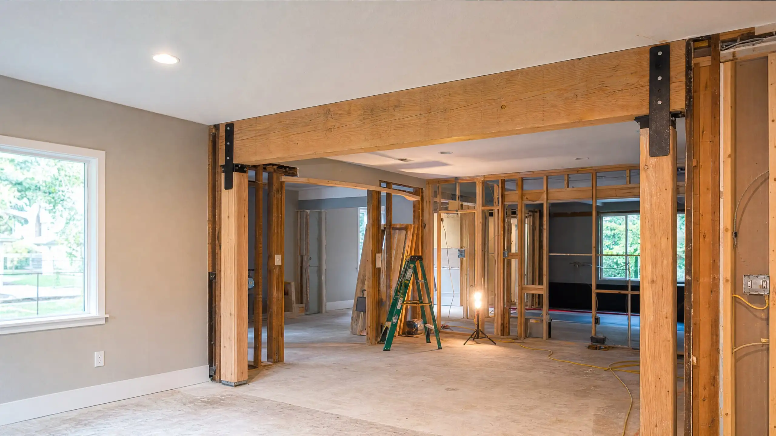 Engineered beam installed across an opened wall between a house and an addition, supported on new posts