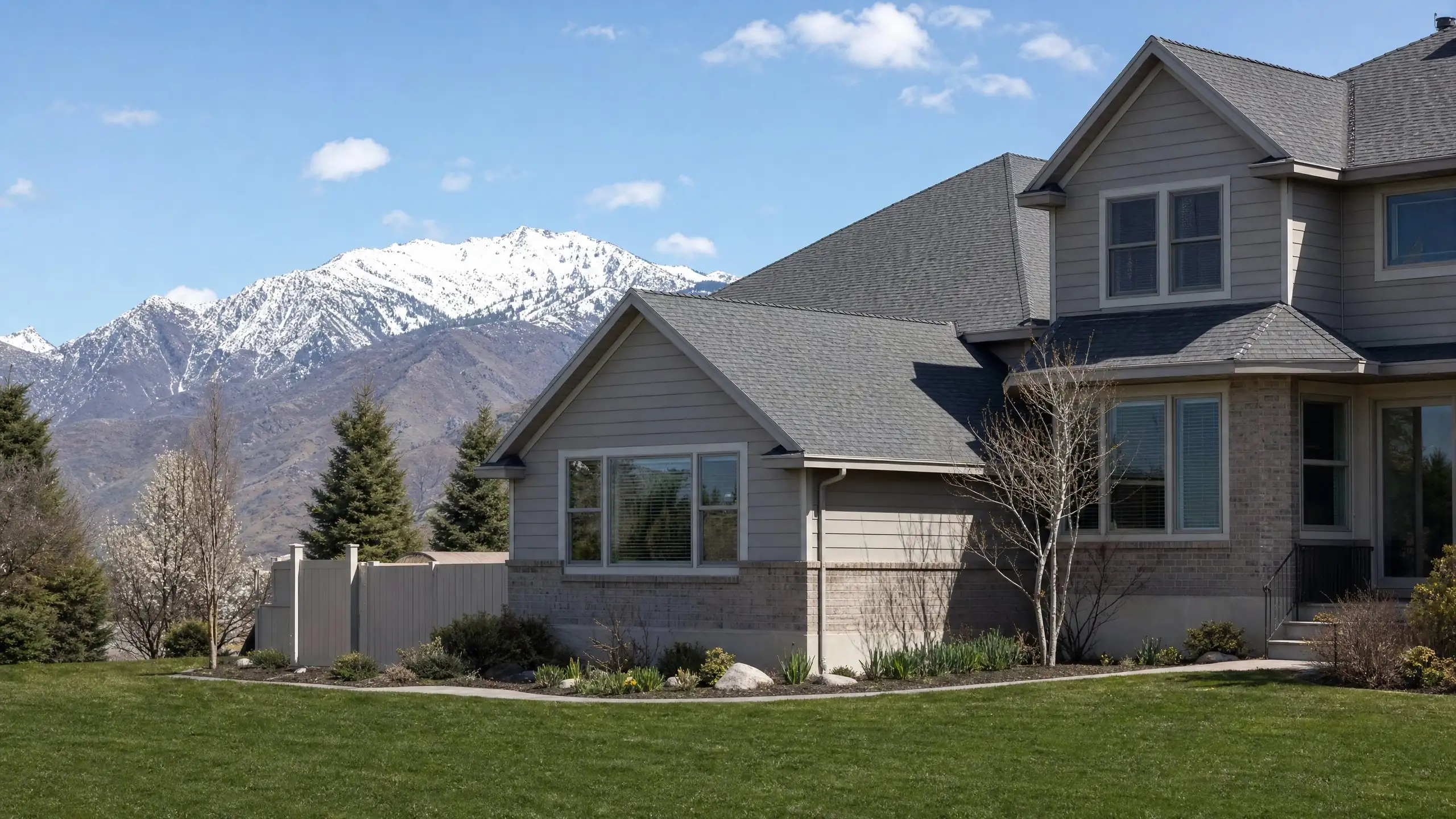 Foothill home with a family room addition and steep matching roof, snow on the peaks behind
