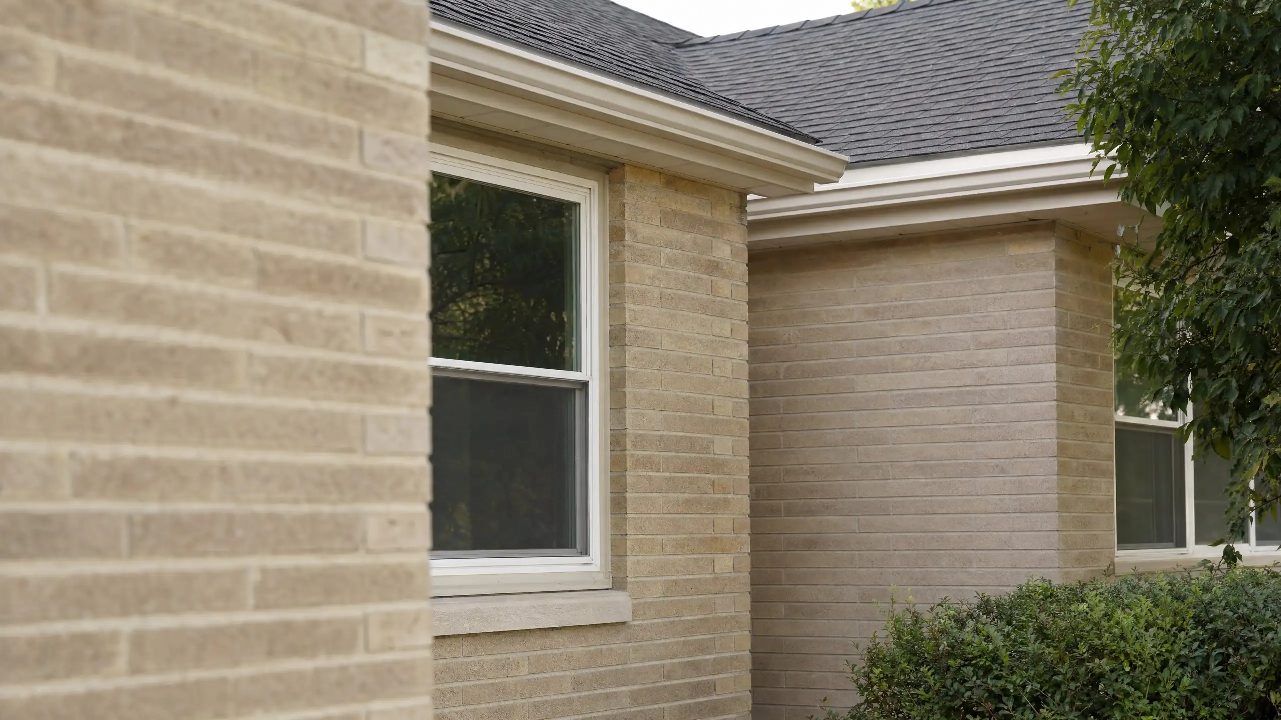 Close view of new brick toothed into original brick where an addition meets the house, with matching trim