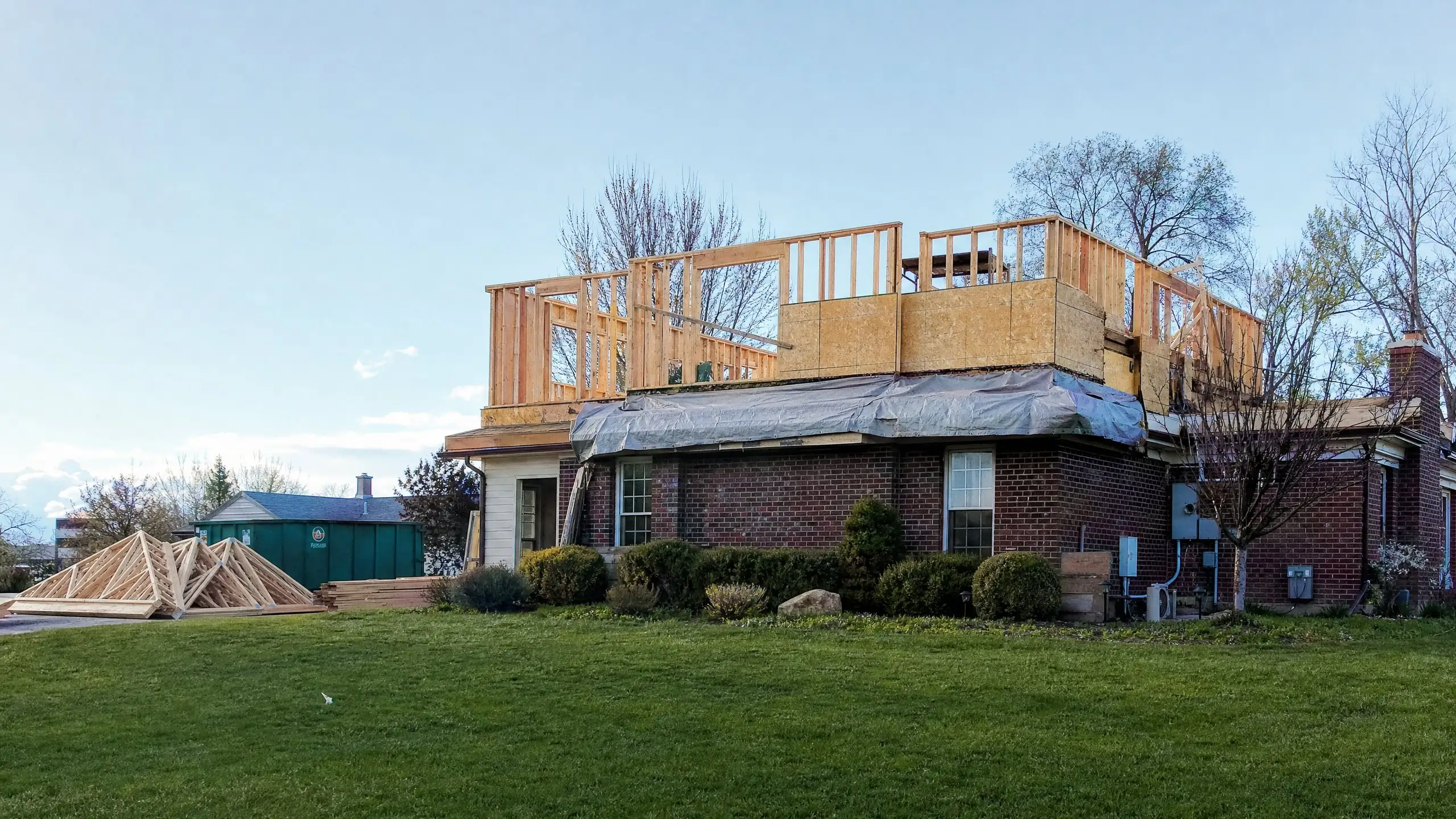 Brick rambler with its roof removed and new second-floor walls framed on top during construction
