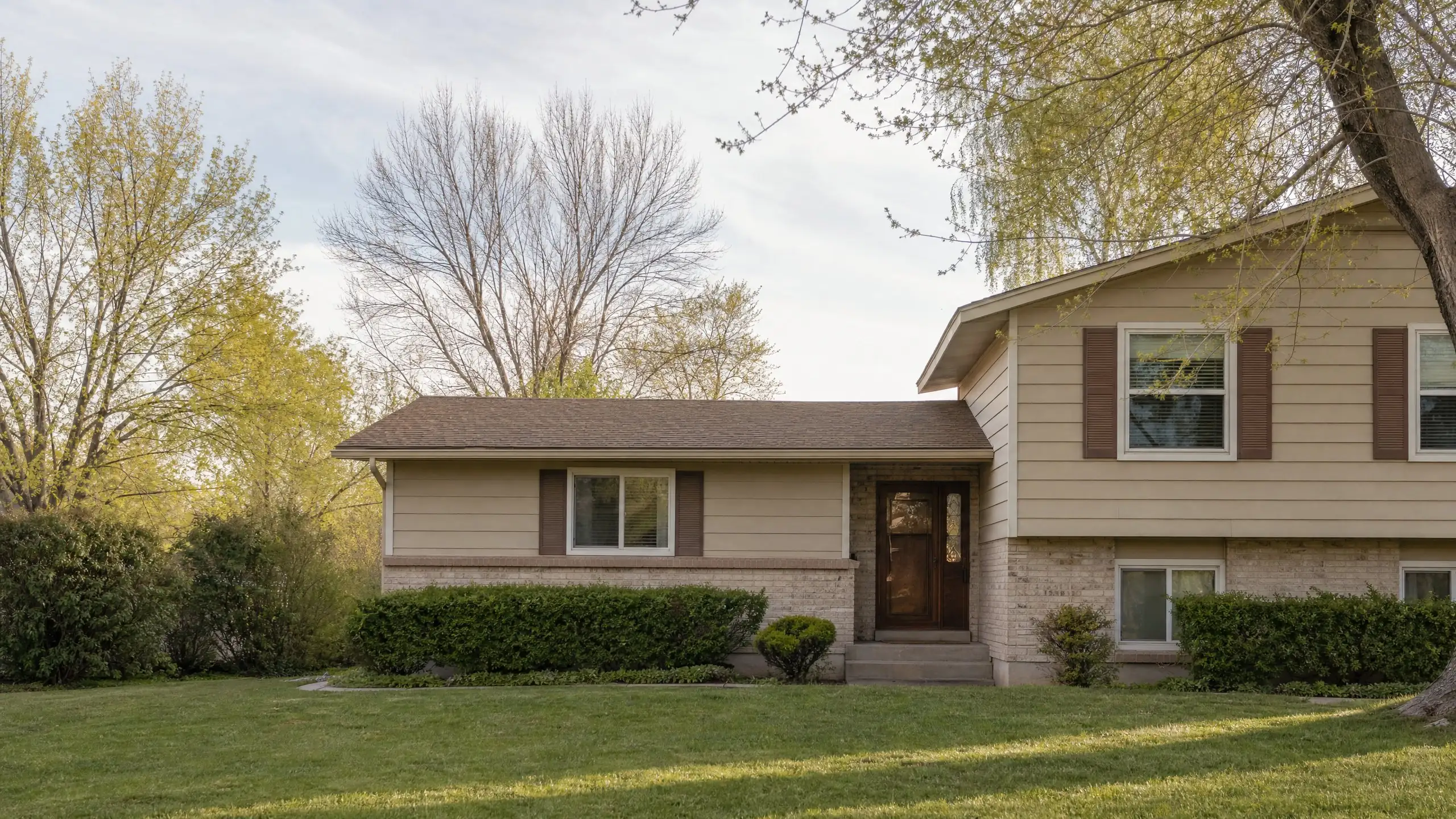 Split-level home with a single-story bedroom wing added to the side in matching siding and roof pitch