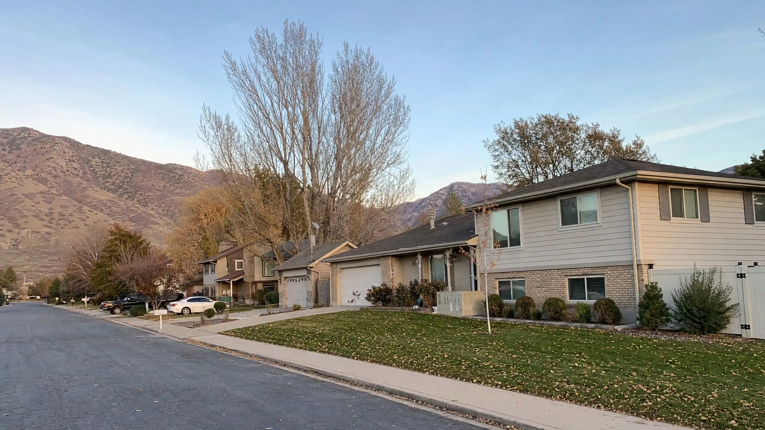 Residential street rising toward the foothills, with a home that has a matching addition beside the garage
