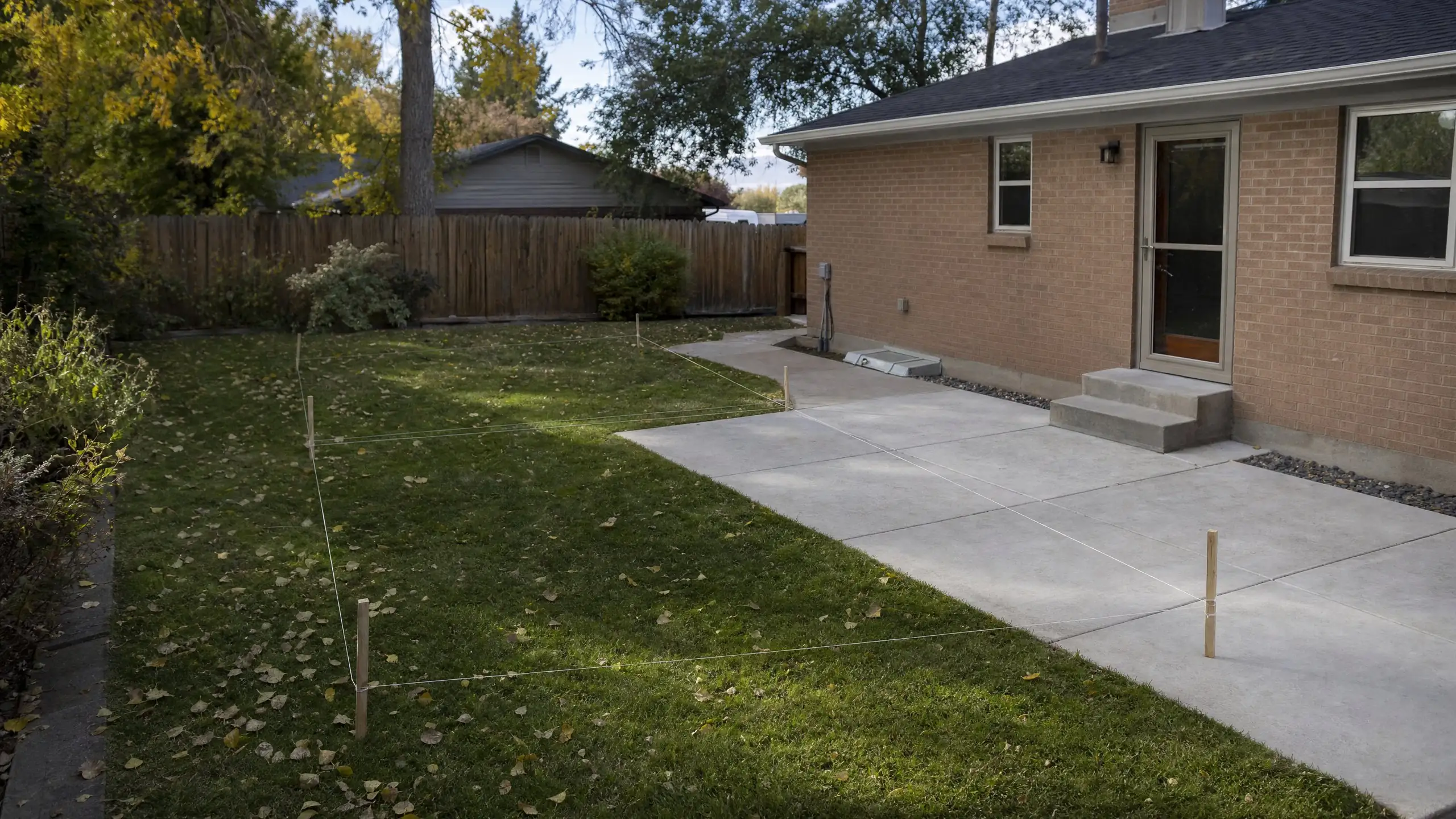 String lines and stakes marking the footprint of a planned addition in a backyard